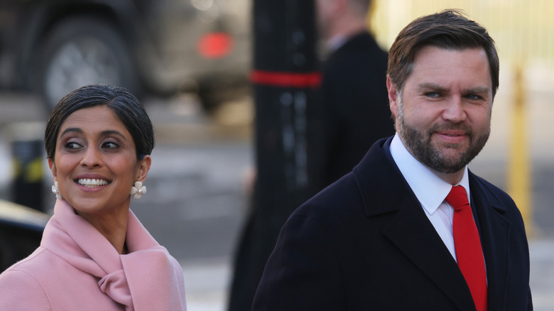 Usha Vance smiling in a pink coat next to JD Vance who's wearing a suit.
