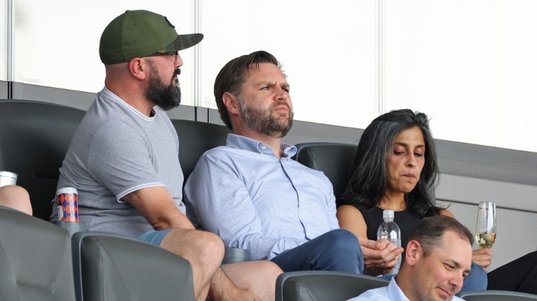 JD Vance and Usha Vance sitting with someone (far left) in the stands at a sporting event