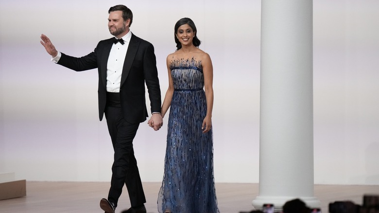 Usha Vance smiling in a blue dress while holding hands with JD Vance, wearing a tux, while they both attend the Commander-in-Chief ball.