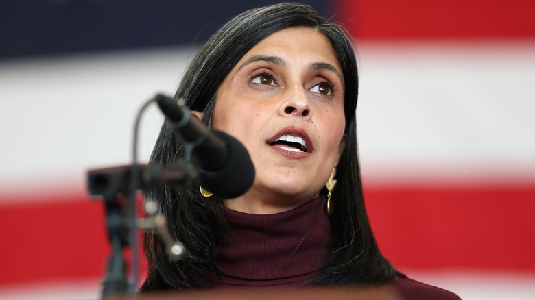 Usha Vance speaking into microphone in front of American flag backdrop
