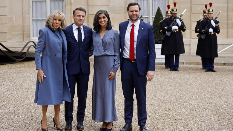 Brigitte Macron, Emmanuel Macron, Usha Vance, and JD Vance posing together in front of armed palace guards