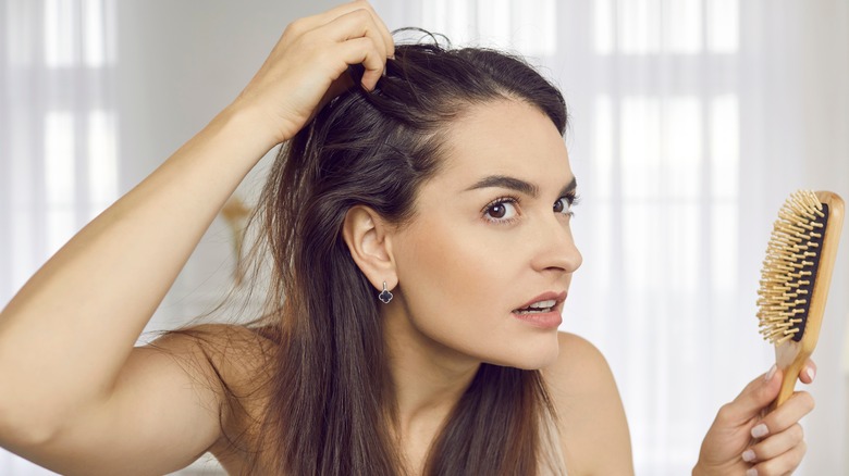 A woman looking at her hair. 