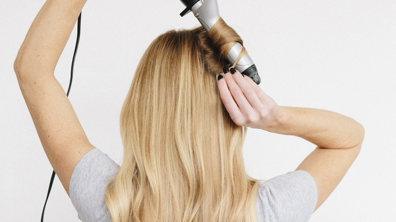 girl with blonde hair curling her hair