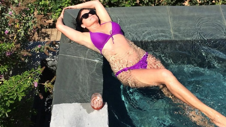Valerie Bertinelli wearing bikini lying against corner of swimming pool
