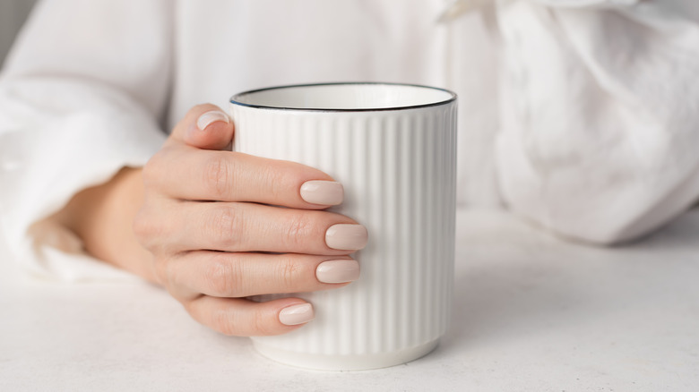 Clean vanilla latte nails on hand holding white mug