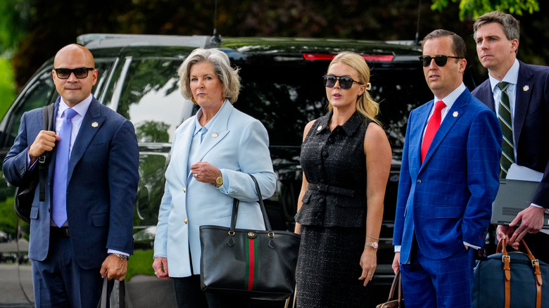 Susie Wiles standing with Karoline Leavitt and other White House staffers