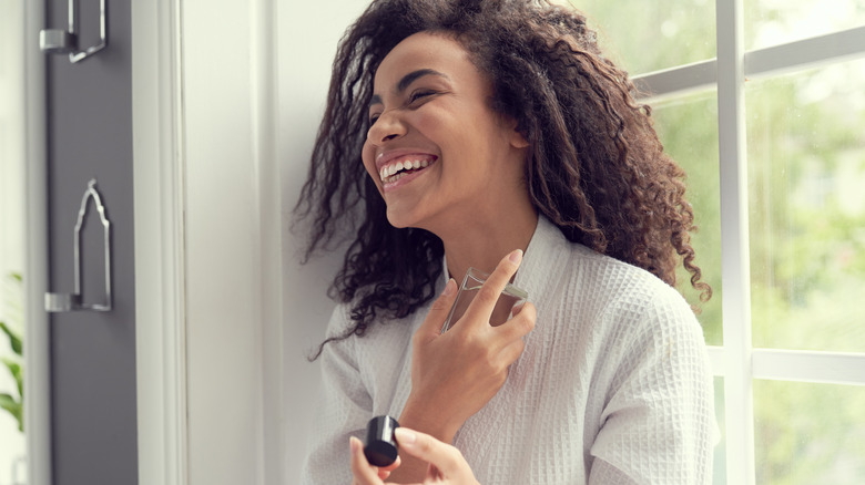 A woman putting perfume on her neck