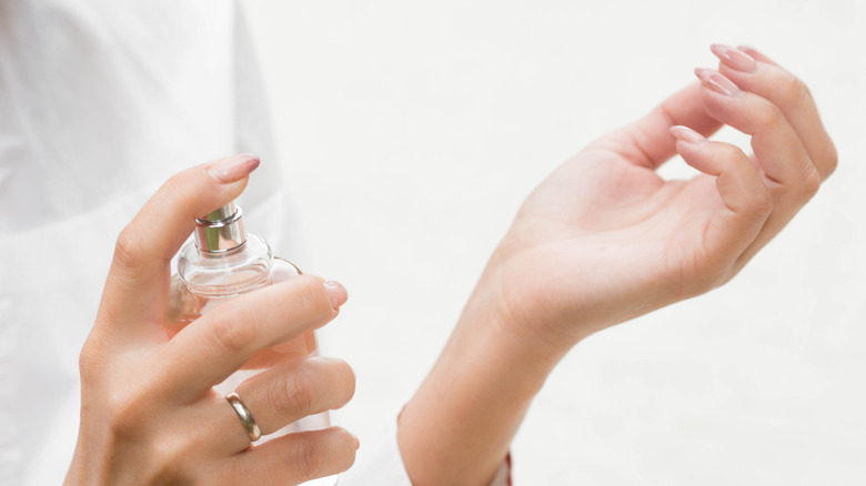 Woman spraying perfume onto wrist 