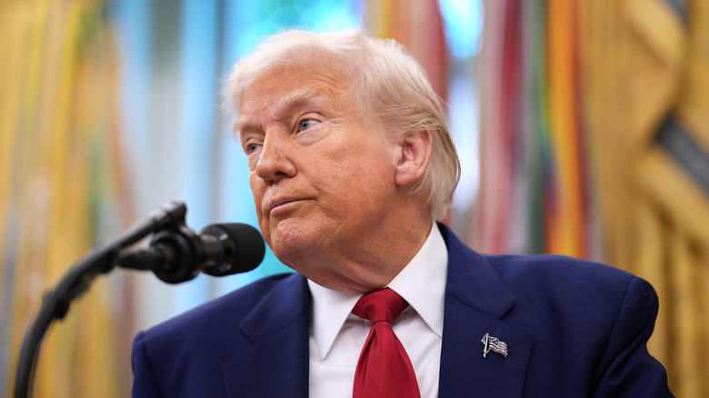 Donald Trump listening to reporters in the Oval Office