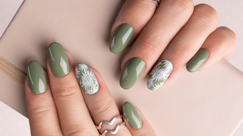 Woman's hands with green oval nails and tropical design