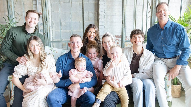 Kristi Noem and Bryon Noem smiling in family photo with their children and grandchildren