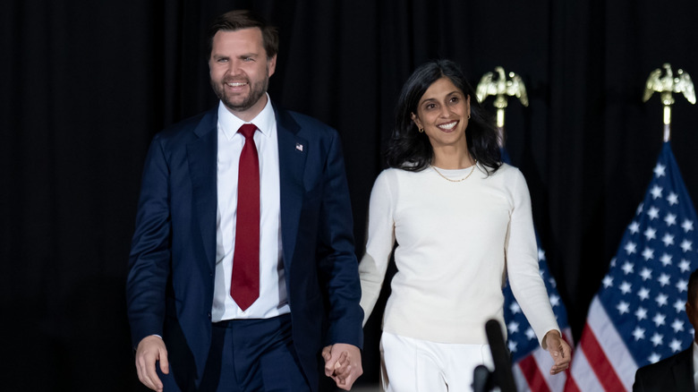 JD and Usha Vance holding hands and walking on stage.