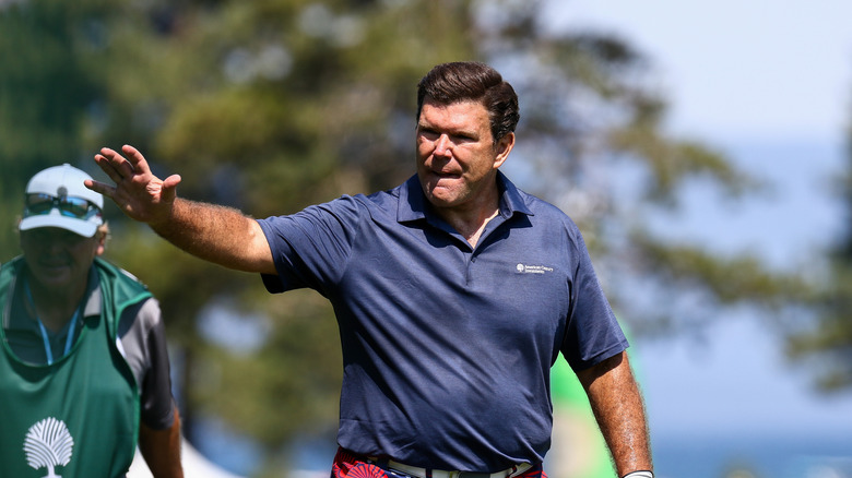 Bret Baier waving to someone off-camera while playing golf
