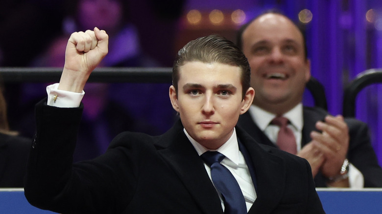 Barron Trump holding up a fist while wearing a suit at his father's inauguration