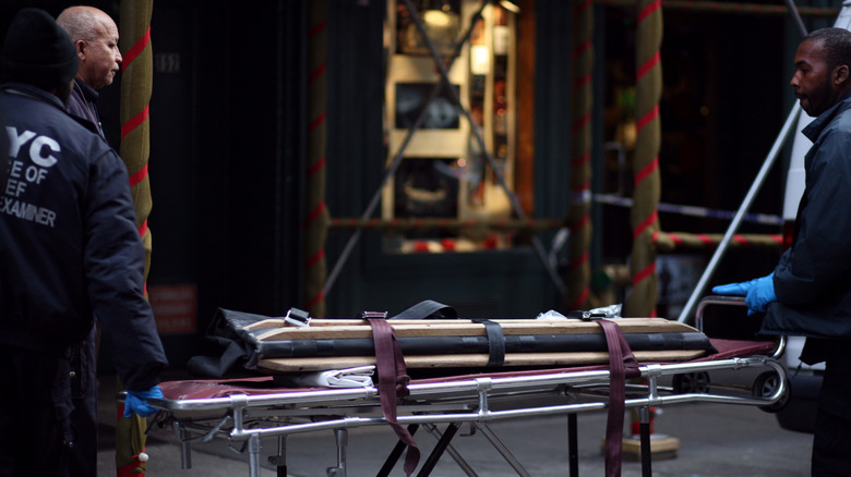 Police with an empty gurney for Mark Madoff's remains on city street