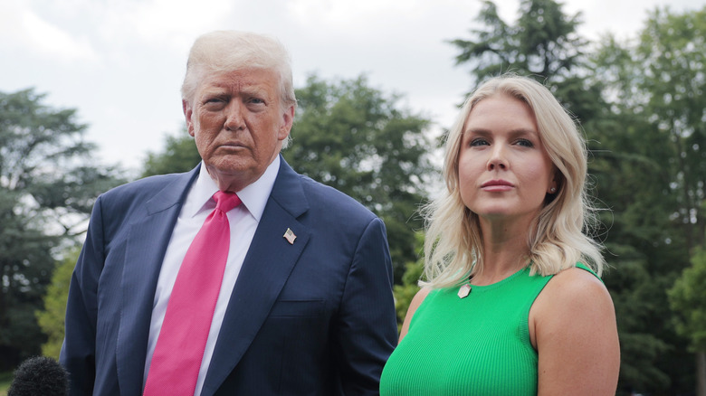 Donald Trump frown beside a smiling Karoline Leavitt outdoors.