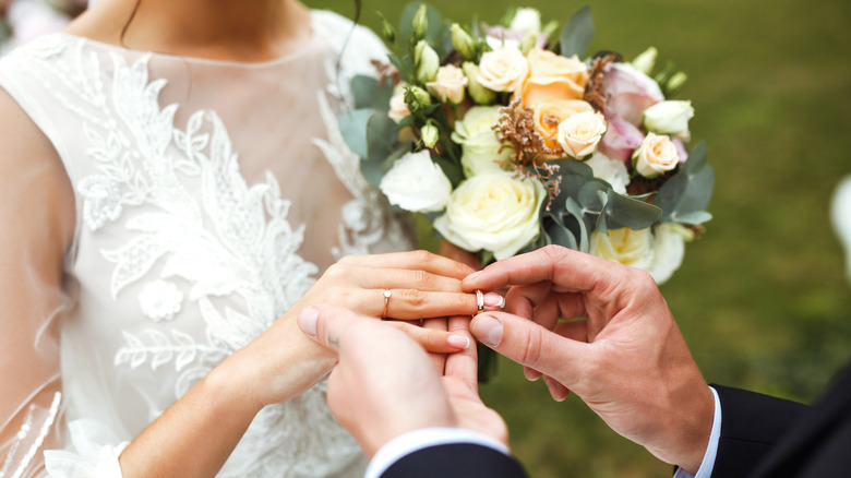 A groom putting a ring on a bride's finger