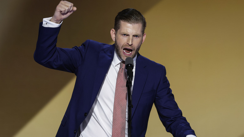 Eric Trump shouting into a microphone while fist pumping the air