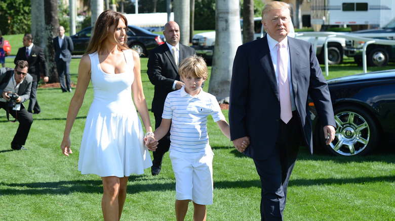 Donald and Melania Trump walking with a young Barron Trump between them