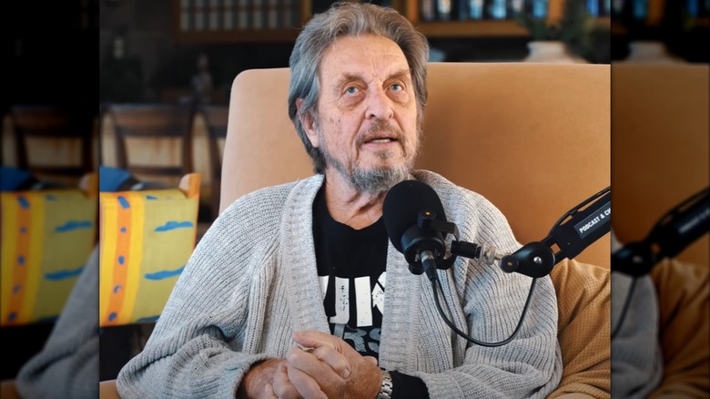 Errol Musk with hands clasped together giving podcast interview