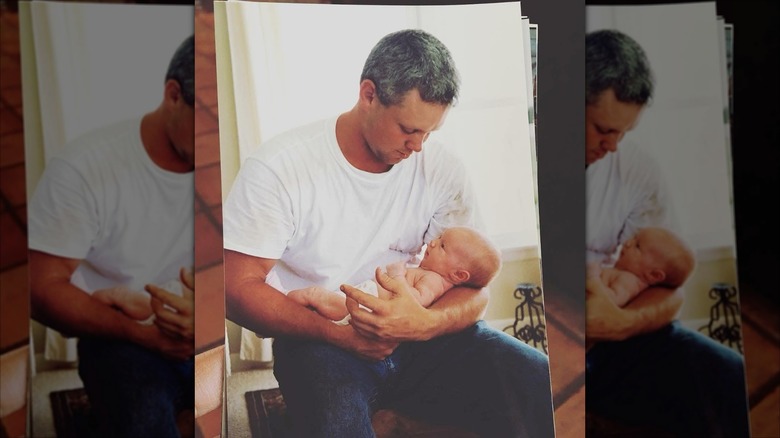 Young Ladd Drummond holding a baby in a white shirt.