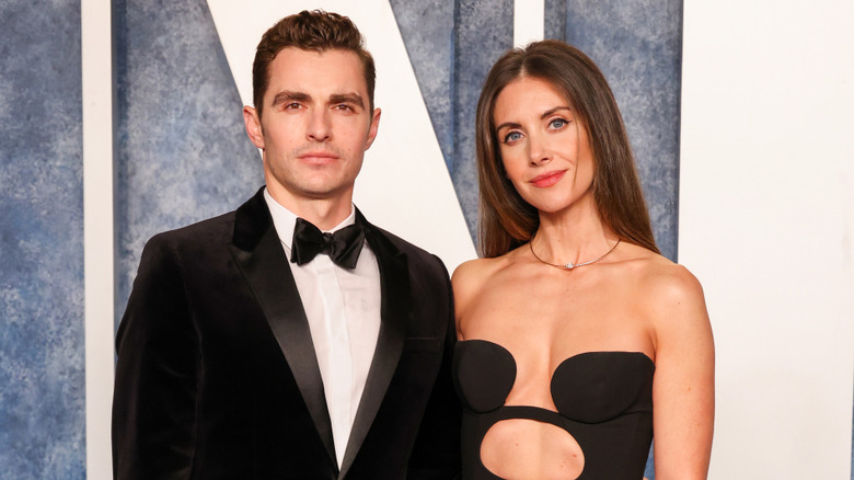 Dave Franco wearing a tux and Alison Brie wearing a black dress with cutouts at the 2023 Vanity Fair Oscar Party