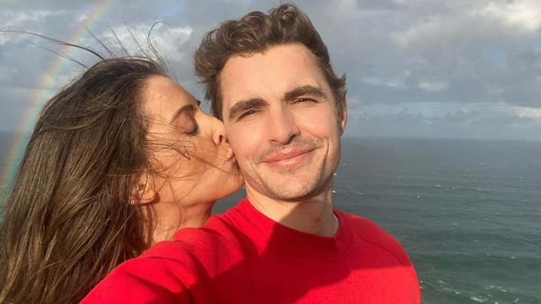 Alison Brie kissing Dave Franco on the cheek in front of the ocean