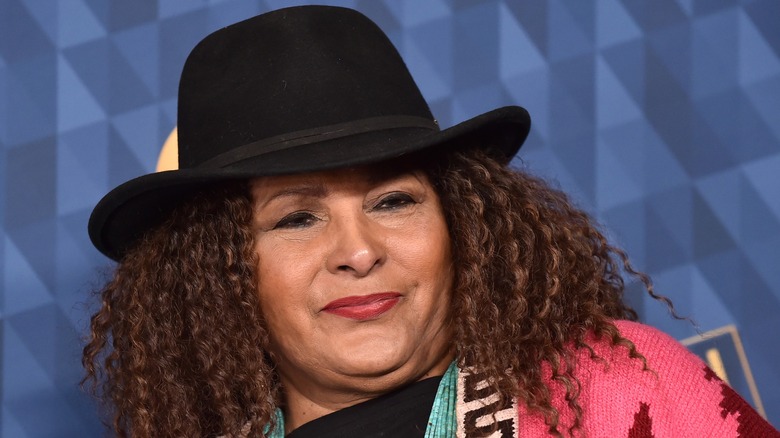 Pam Grier wearing a black hat and colourful outfit at a premiere.