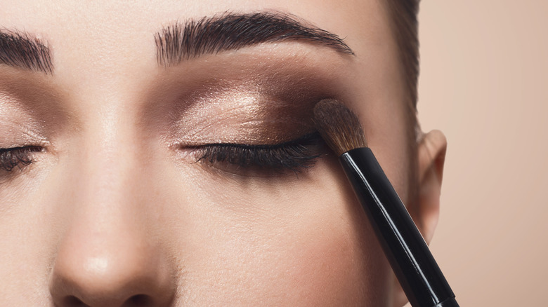 Model applying eyeshadow makeup face