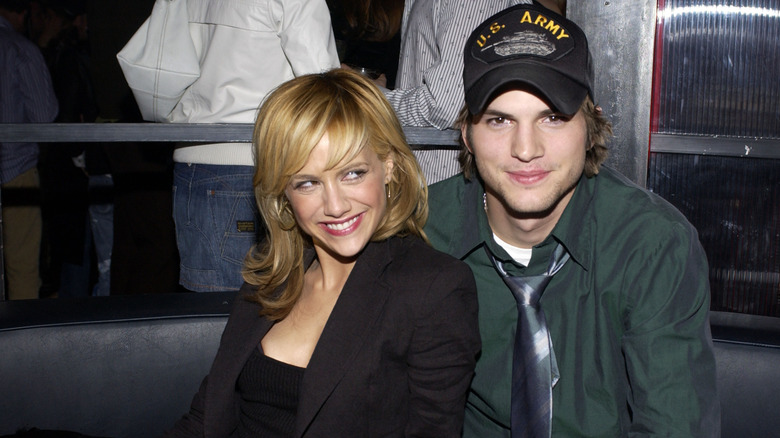 Brittany Murphy and Ashton Kutcher smiling while cuddling up together at an event