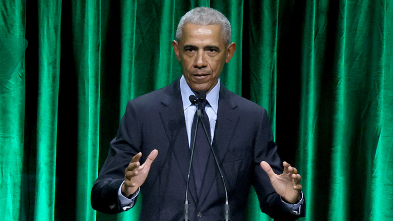 Barack Obama speaking at a podium in 2022 