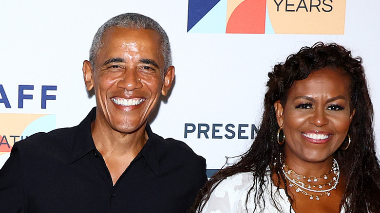 Barack and Michelle Obama posing in front of a banner during film premiere