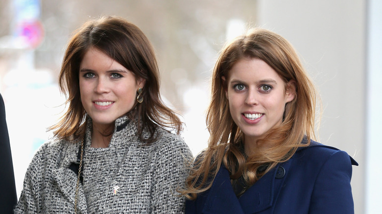 Princess Eugenie and Princess Beatrice smile into a camera