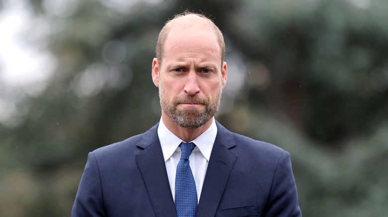 Prince William pulls a concerned-looking face against a green background