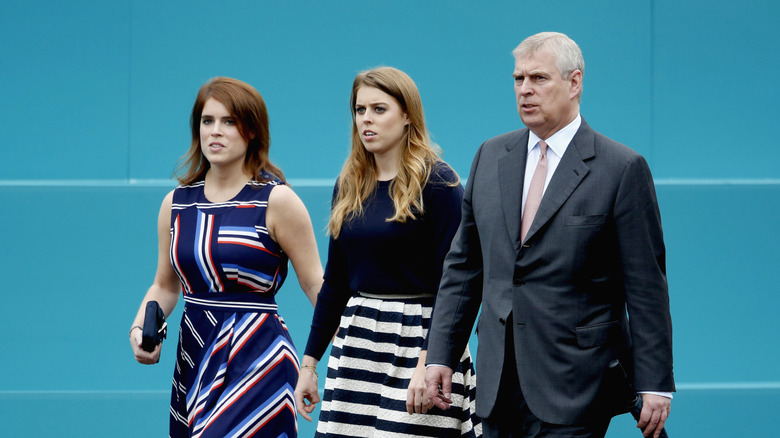 Princess Eugenie, Princess Beatrice, and Andrew Mountbatten-Windsor against a blue background