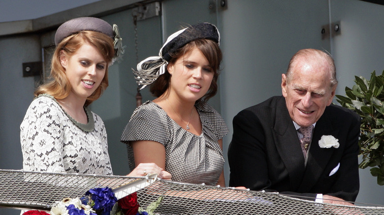 Princess Beatrice, Princess Eugenie, and Prince Philip stand on a balcony