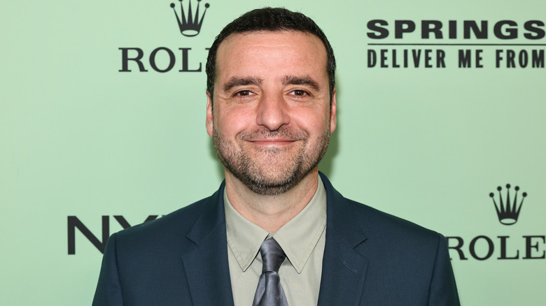 David Krumholtz smiling for photos in a dark green suit