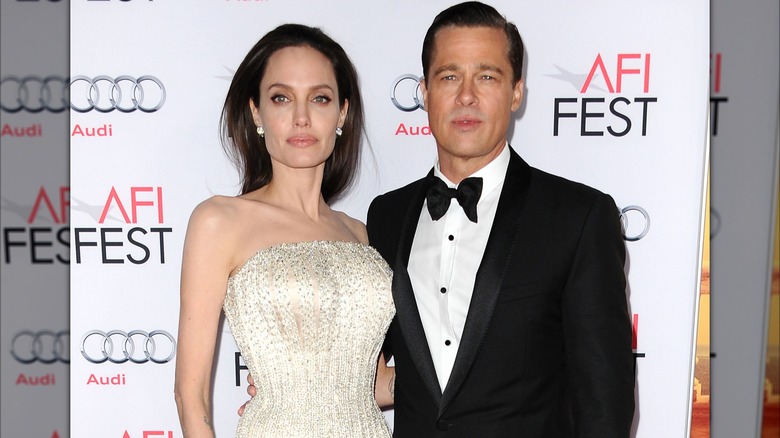 Brad Pitt and Angelina Jolie posing together with serious faces on the red carpet.