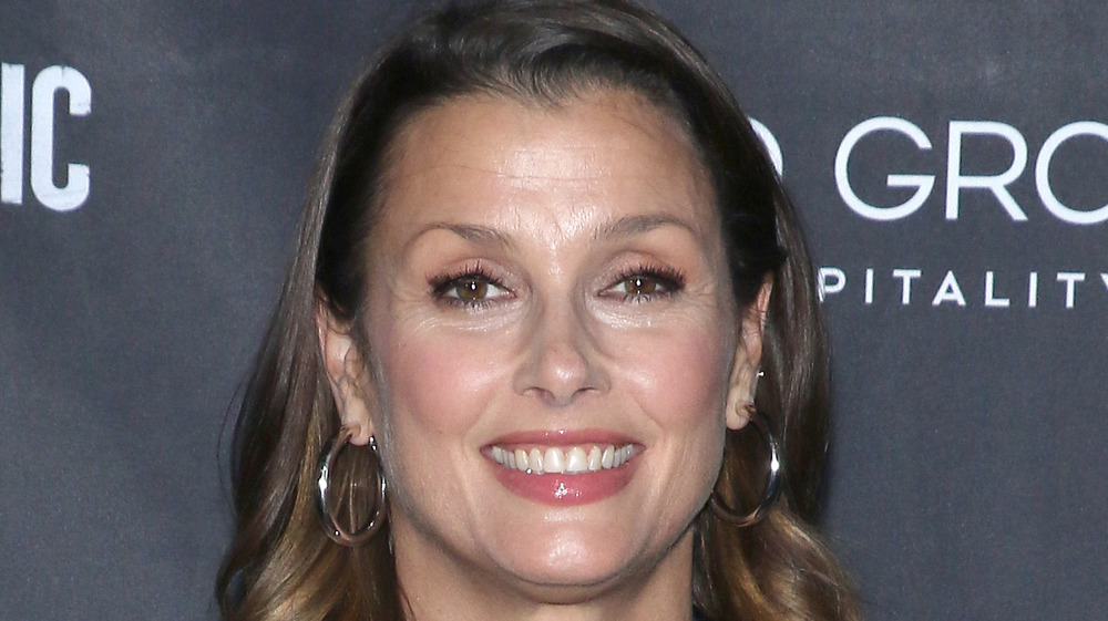 Bridget Moynahan smiling with gold hoop earrings