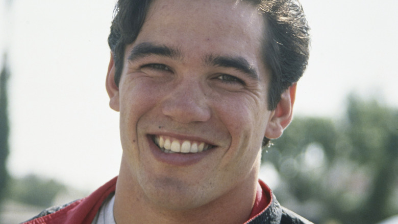 A young Dean Cain smiles for a photo in an outdoor setting