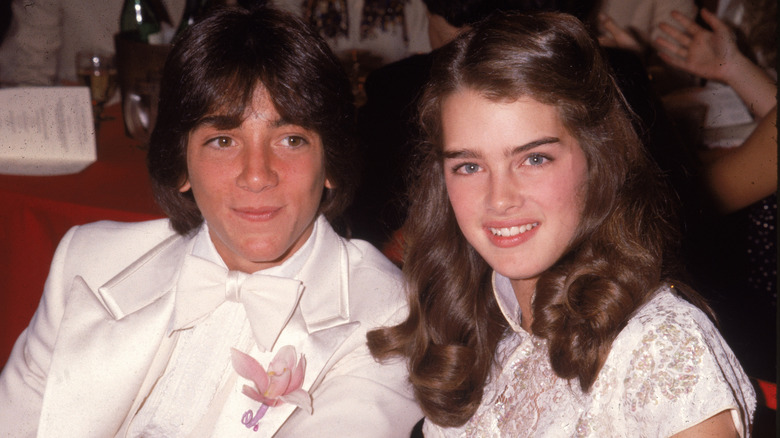 A young Scott Baio and Brooke Shields sit side-by-side as they smile for a photo