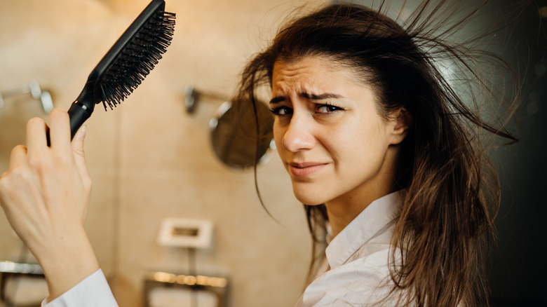 Woman trying to brush dull hair
