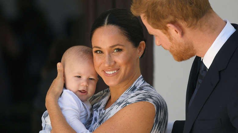 Prince Harry looking on as Meghan Markle holds Prince Archie