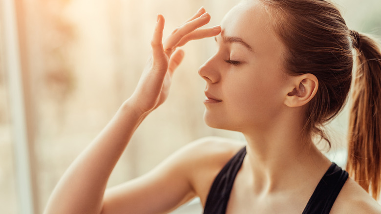 A woman touching her third eye area 