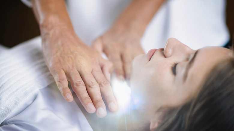 Hands over a glowing throat chakra on a woman 