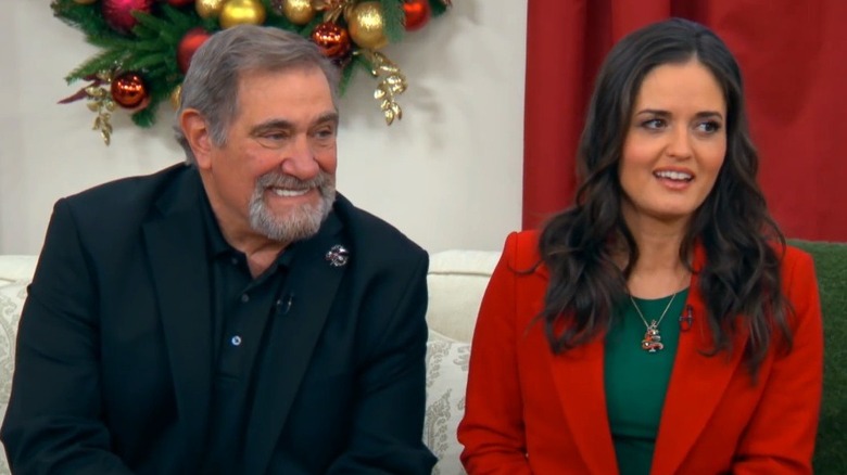 Dan Lauria smiling beside Danica McKellar during a Hallmark Channel interview.