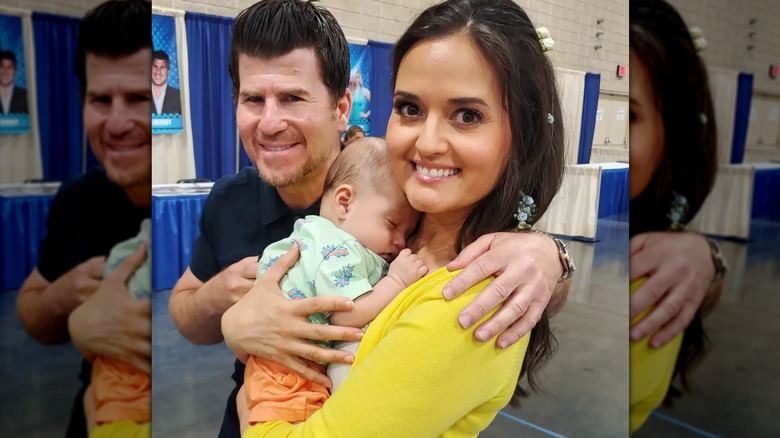 Jason Hervey placing his arm around Danica McKellar as she holds his grandson.