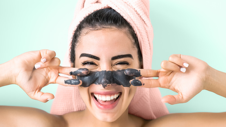 Woman smiling while applying a face mask