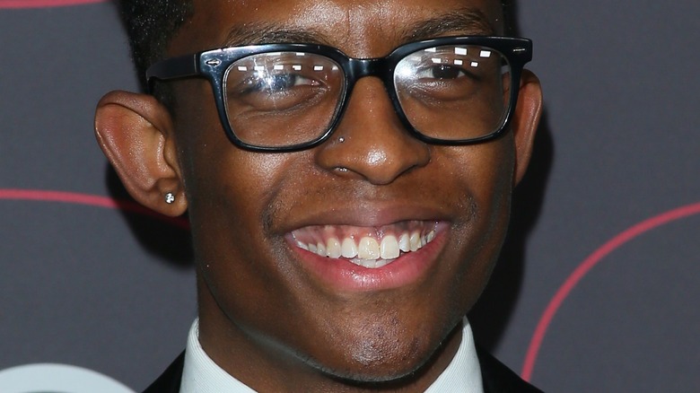 Breland smiles with glasses and stud earrings