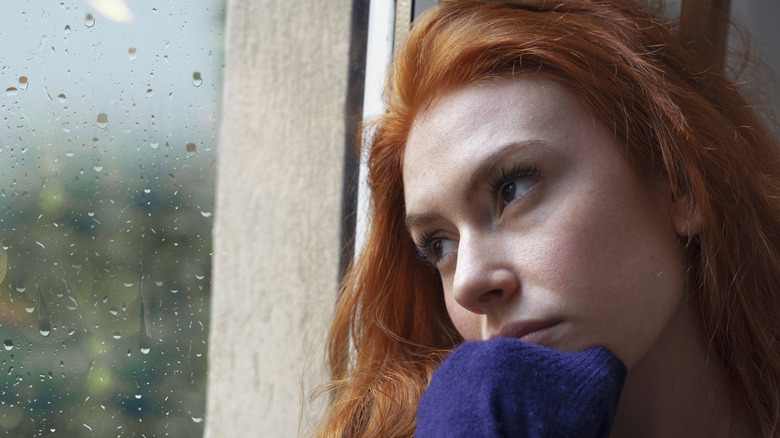 Worried woman near window 